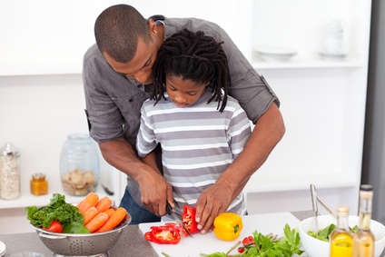 Loving father helping his son cut vegetables